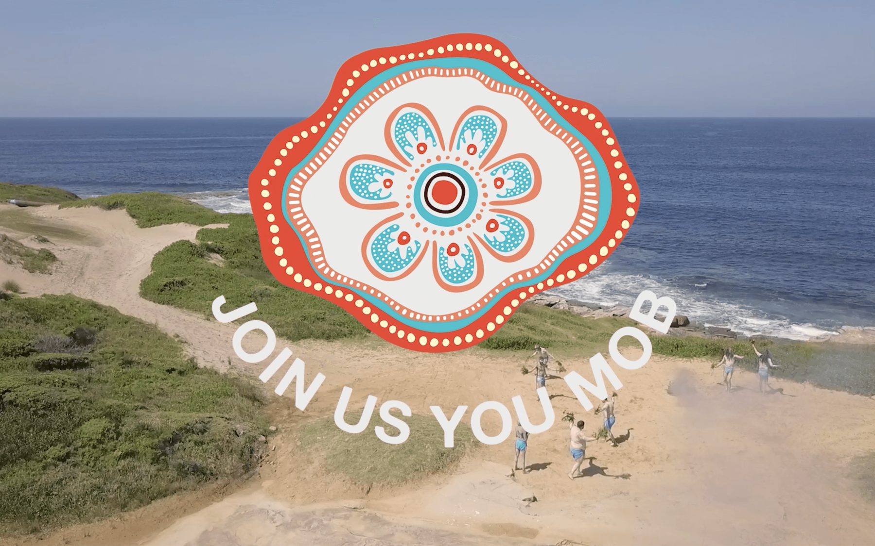 Aerial shot of ceremony dancers on the dunes with AHMRC campaign branding