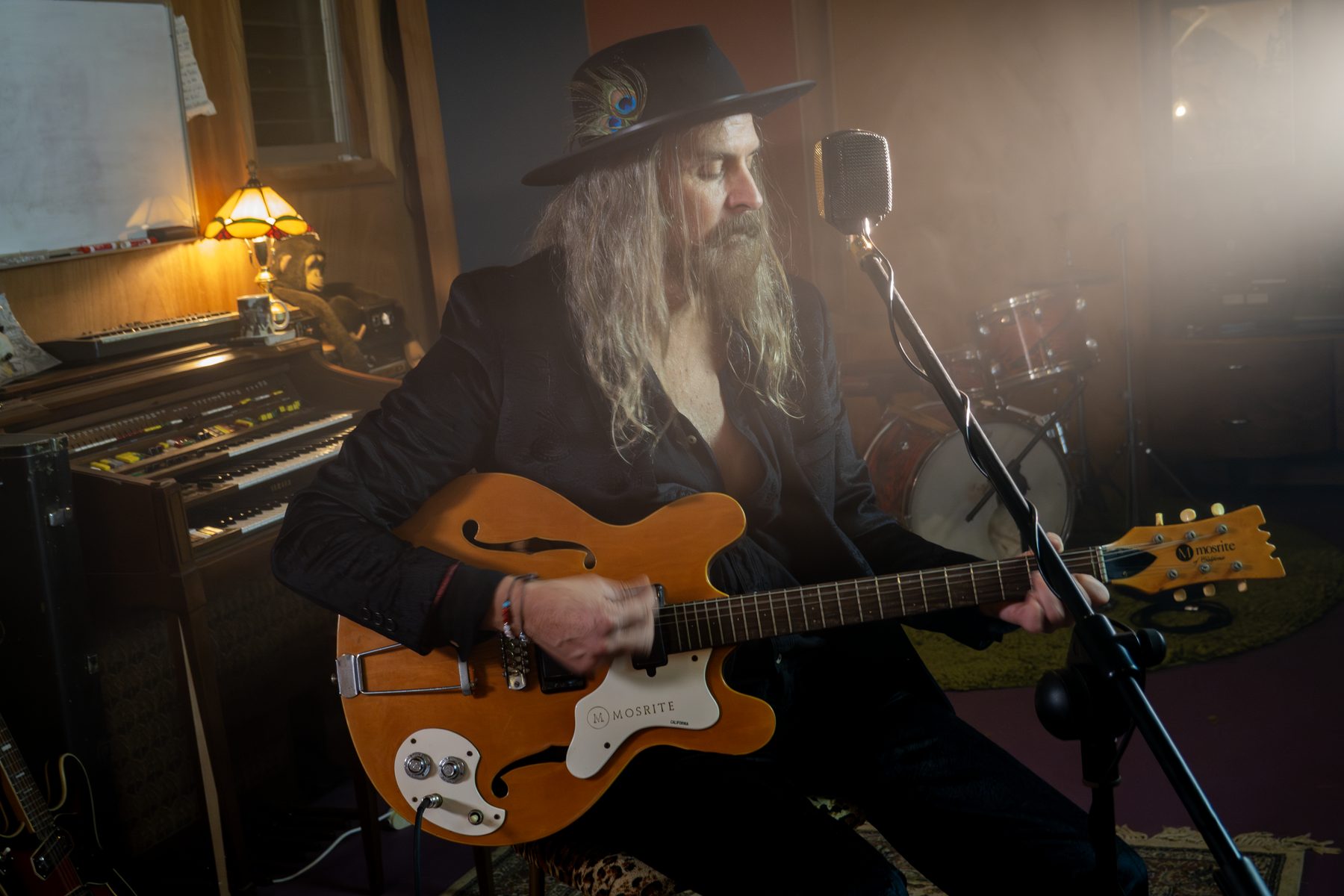 Musician playing guitar in a recording studio at the microphone